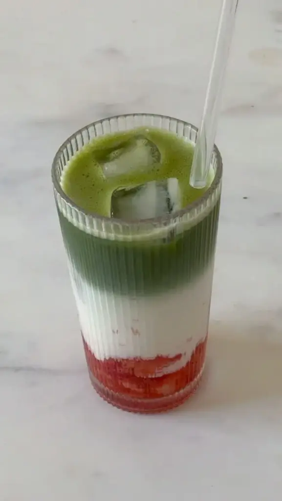 Layered green, white, and red iced drink in a ribbed glass