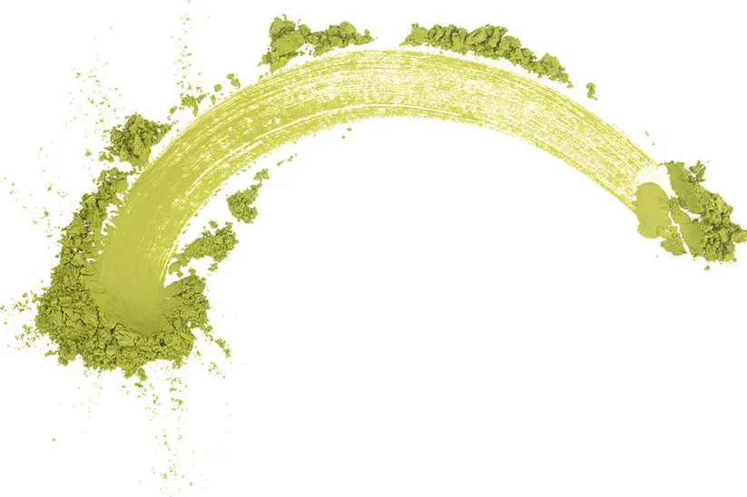Curved sweep of green matcha powder with scattered clumps on a white background