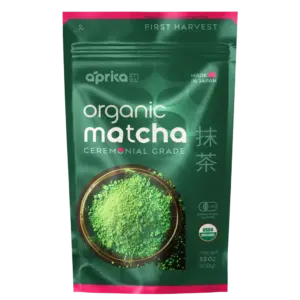 Green and pink Aprika organic ceremonial grade matcha pouch with a bowl of green powder