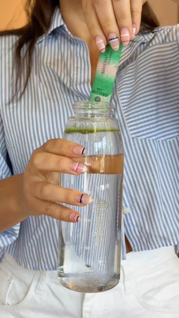 Person placing an O'sulloc Matcha Glow packet into a clear water bottle