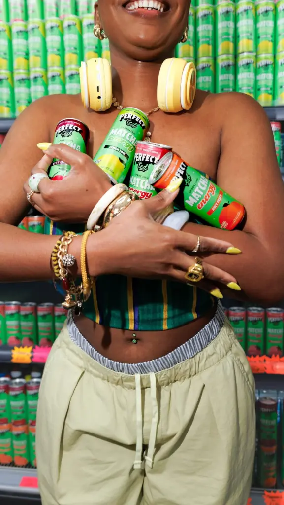 Smiling woman with yellow headphones holding four assorted PerfectTed cans