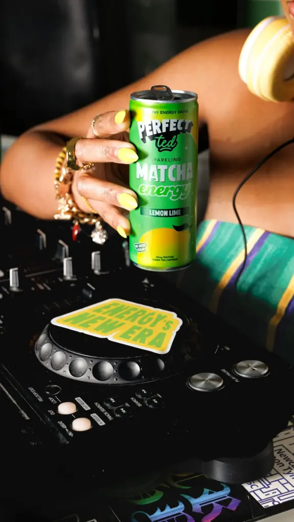 Hand holding a green PerfectTed Lemon Lime matcha can above a DJ deck
