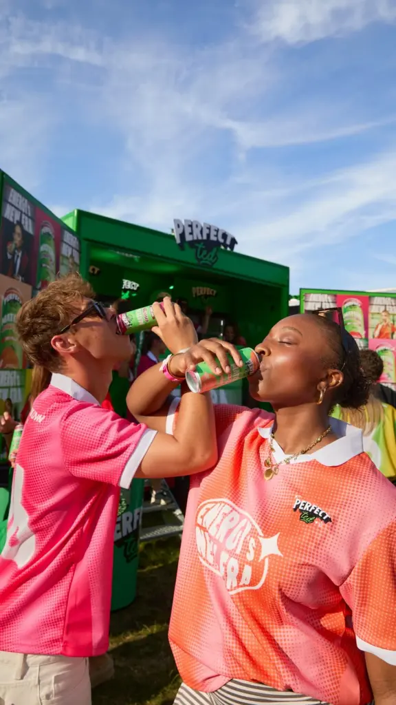 Two people in pink and orange shirts drinking PerfectTed cans outdoors