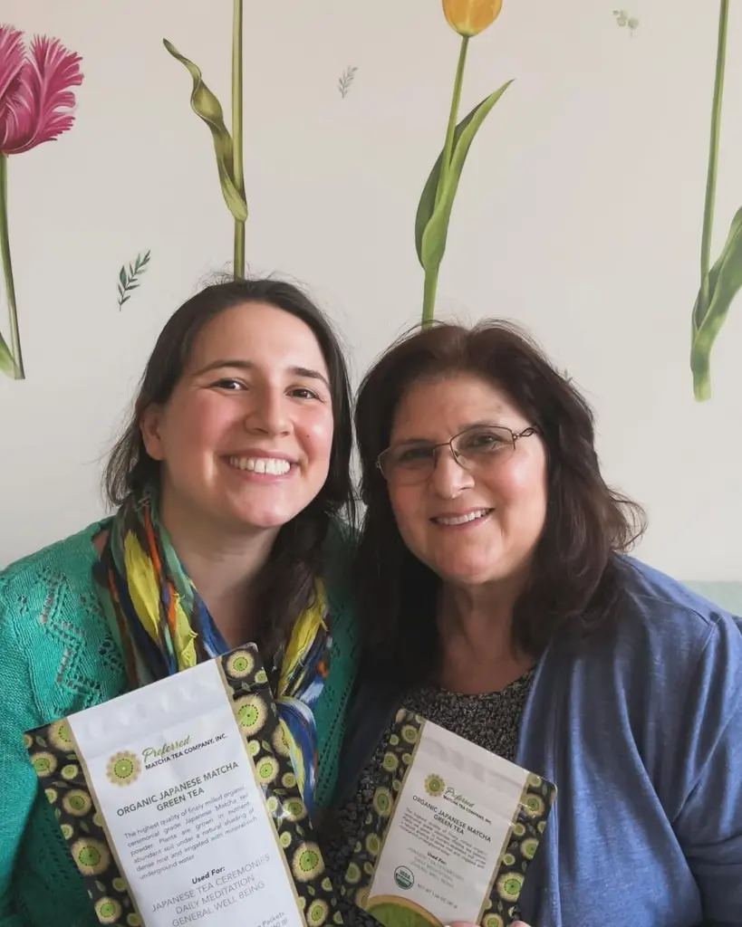 Two smiling women holding packages of Preferred organic Japanese matcha green tea
