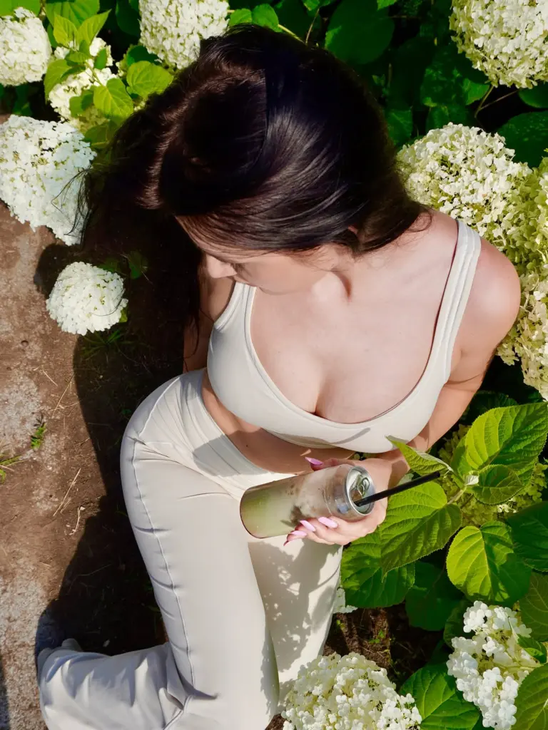 Overhead view of a woman holding an iced drink among white hydrangeas