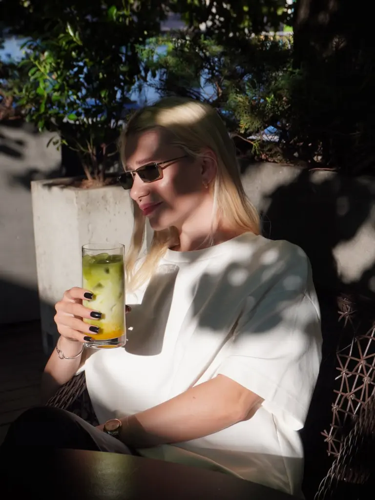 Woman in sunglasses holding a layered green iced drink