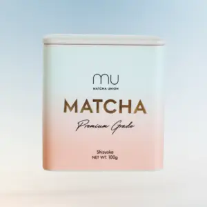 Front view of a white and pale pink Matcha Union Premium Grade matcha tin