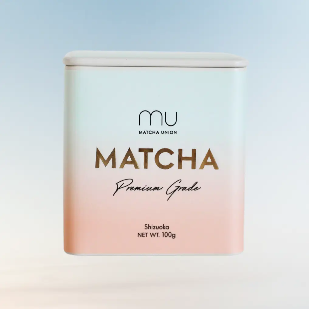 Front view of a white and pale pink Matcha Union Premium Grade matcha tin