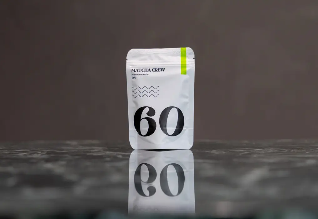 White Matcha Crew No. 60 Premium Matcha 40 g pouch reflected on a dark tabletop