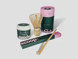 Mamatcha Ritual matcha jar with a bamboo whisk and scoop in pink and dark green packaging