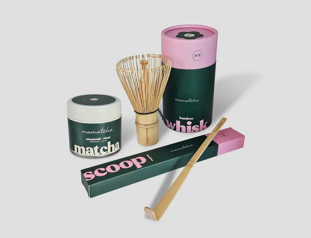 Mamatcha Ritual matcha jar with a bamboo whisk and scoop in pink and dark green packaging