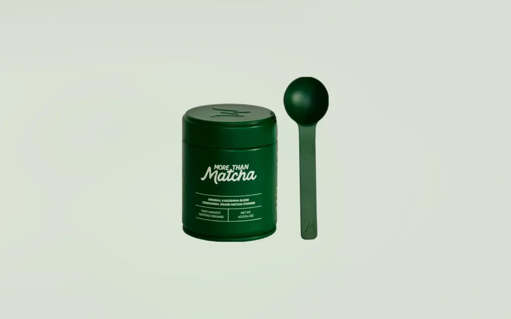 More Than Matcha ceremonial matcha tin and measuring spoon on a pale green landscape background