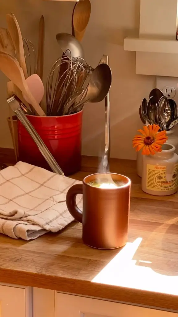 Steaming green drink in a brown mug on a sunlit kitchen counter