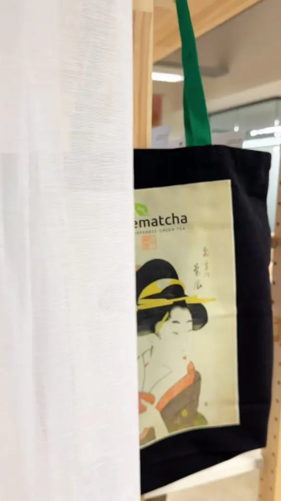 Black tote bag with green handles and a Japanese-style illustrated panel