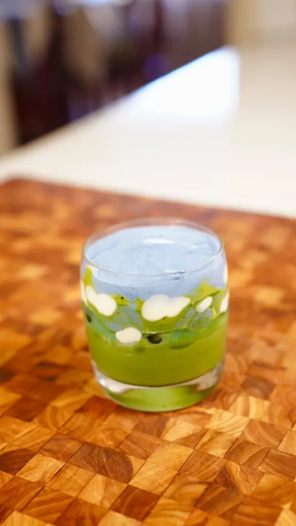 Green matcha dessert with white dollops in a clear glass
