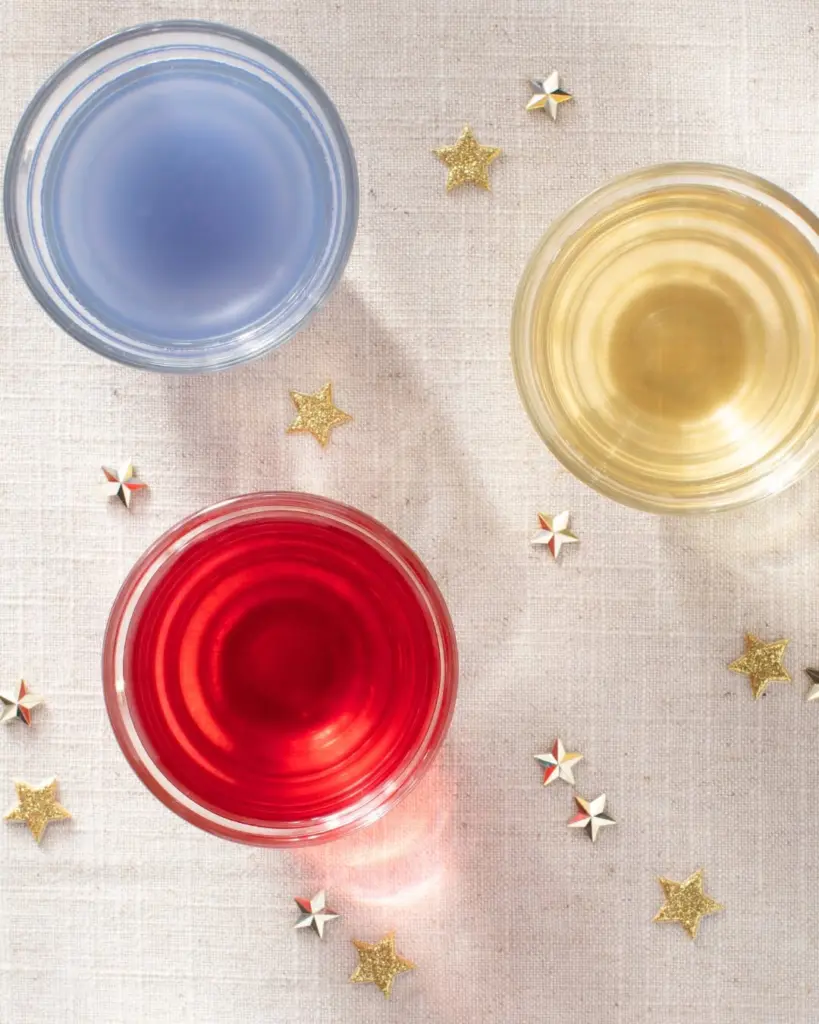 Overhead view of blue, gold, and red tea in glasses surrounded by decorative stars