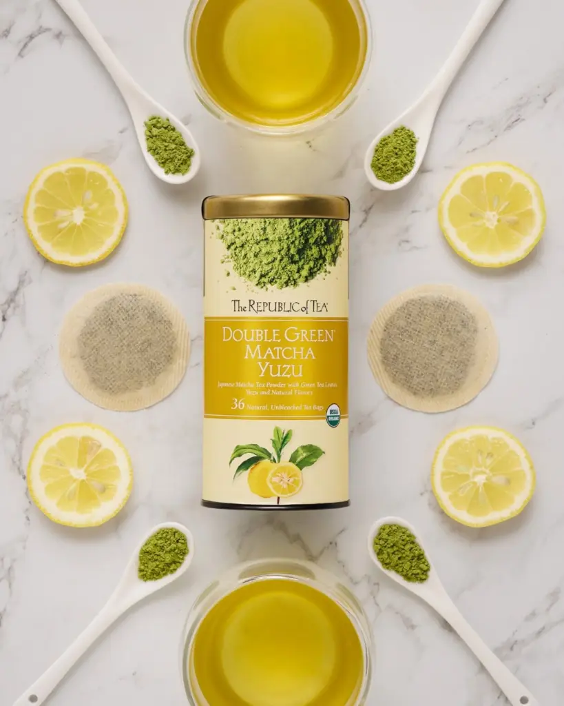 Double Green Matcha Yuzu tea tin surrounded by brewed tea, matcha powder, tea bags, and lemon halves