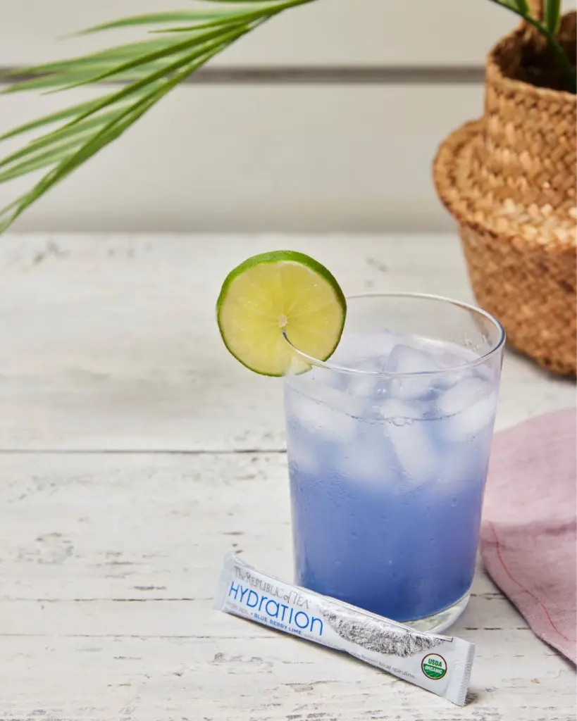Blue iced drink with a lime wheel beside a Republic of Tea Hydration packet