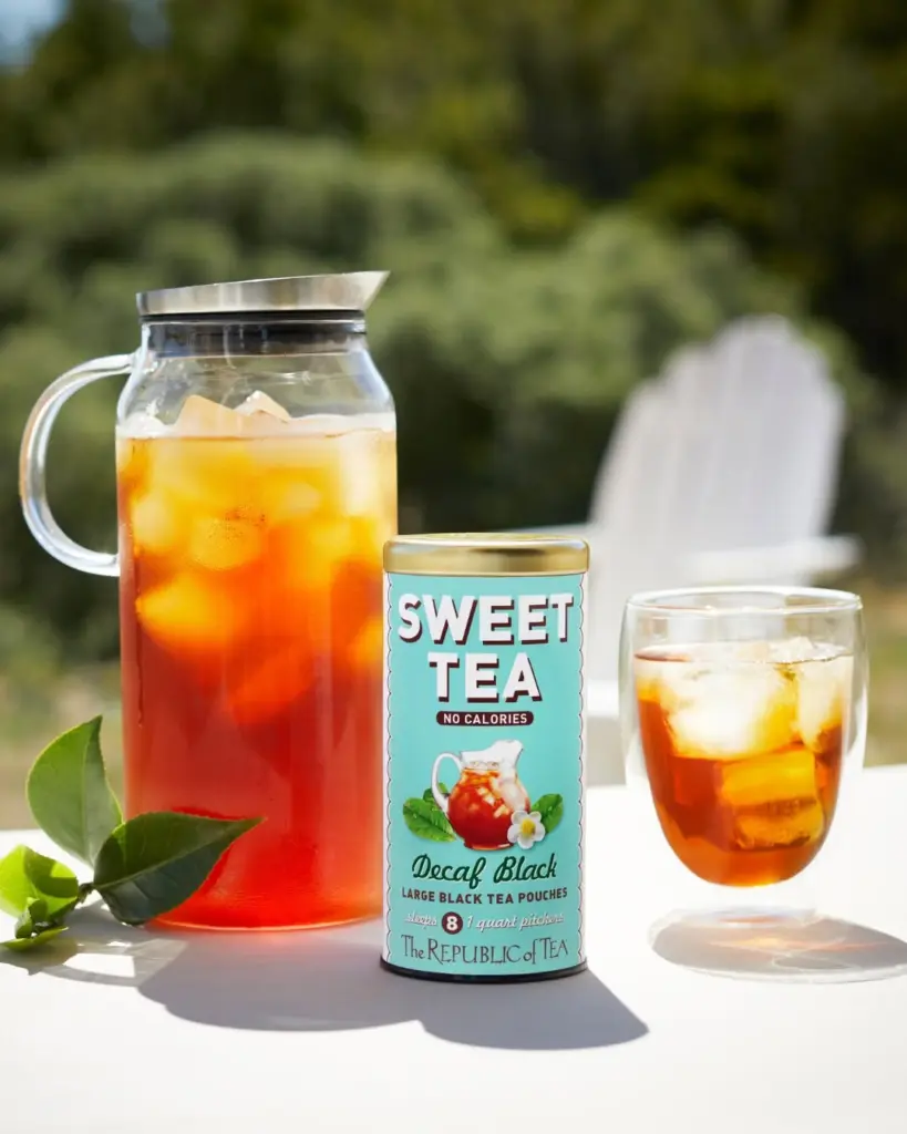 Sweet Tea Decaf Black tin between a pitcher and glass of iced tea on an outdoor table