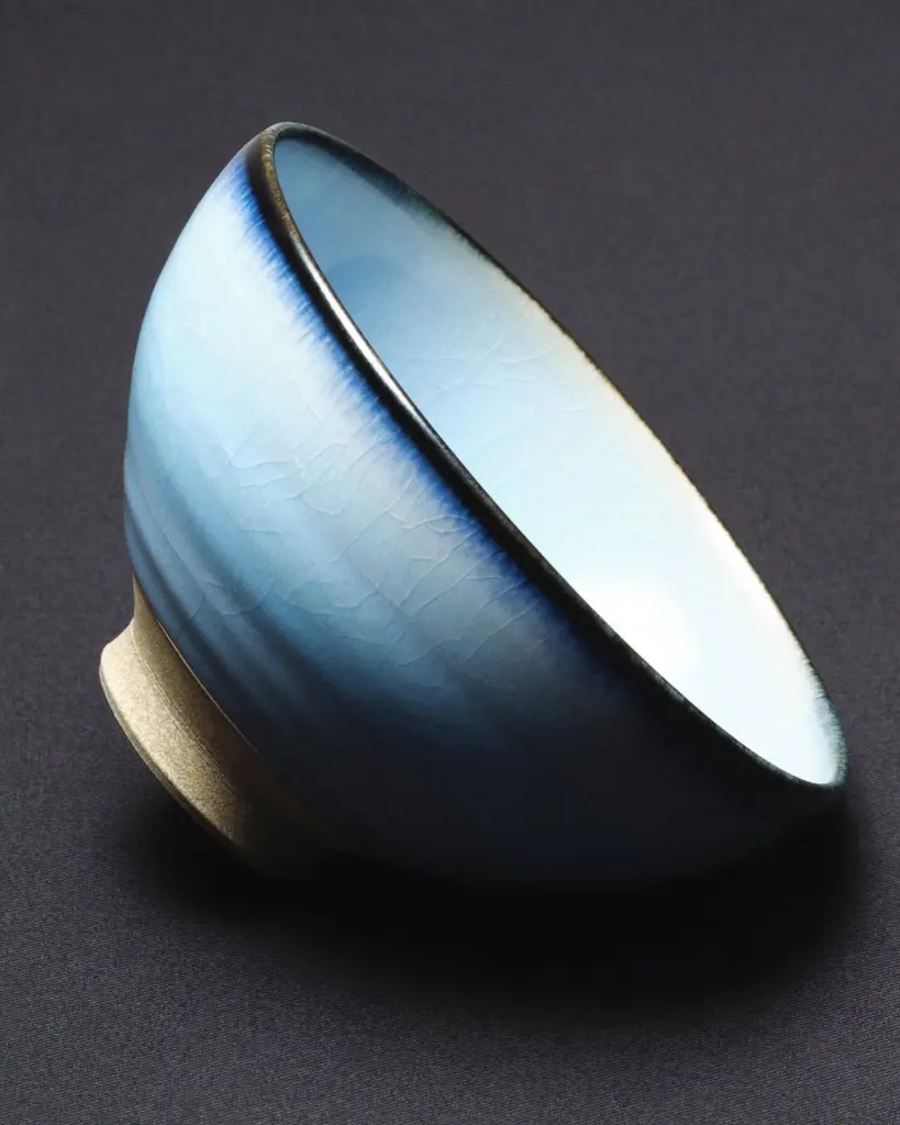 Blue glazed ceramic bowl tilted against a dark background