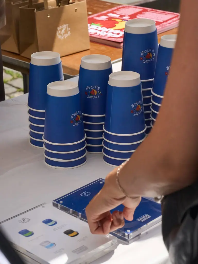 Stacks of blue Rocky's Matcha paper cups on a market table