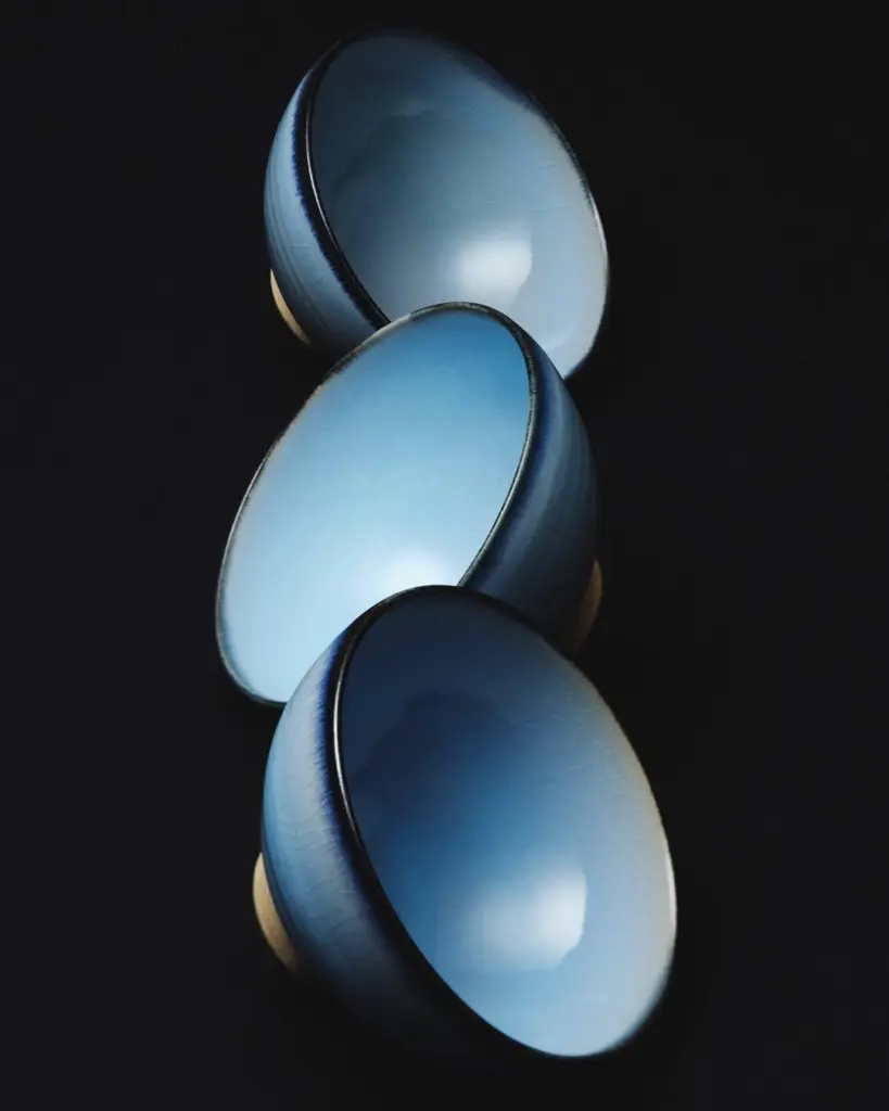 Three glossy blue ceramic bowls arranged on a black background