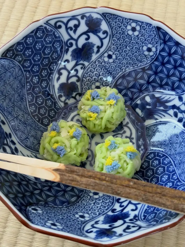 Three green sweets with tiny blue and yellow flowers on a blue-and-white plate