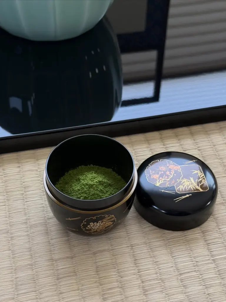 Bright green matcha powder in an open black lacquer container