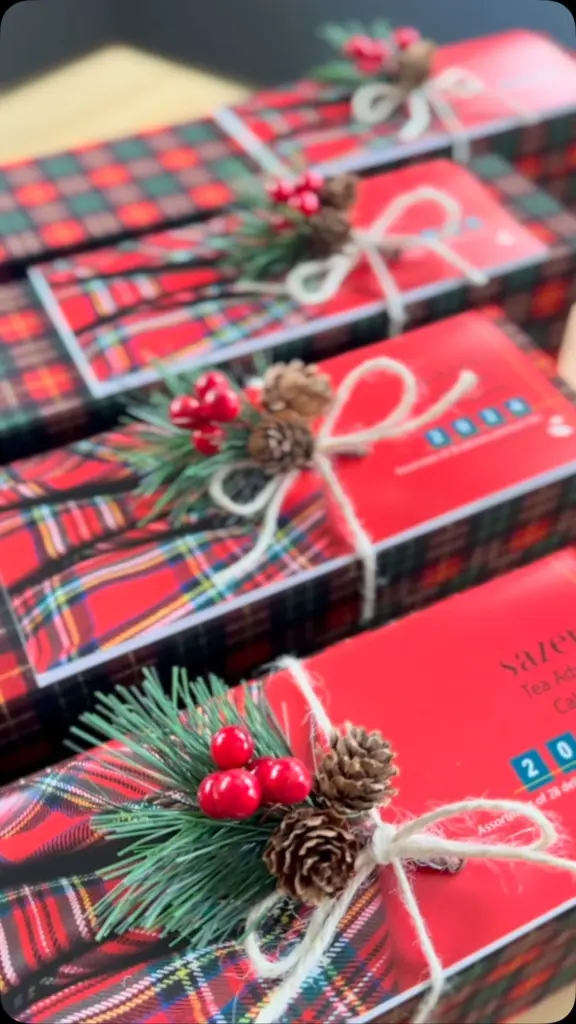 Tartan gift boxes tied with white cord and decorated with pinecones and red berries