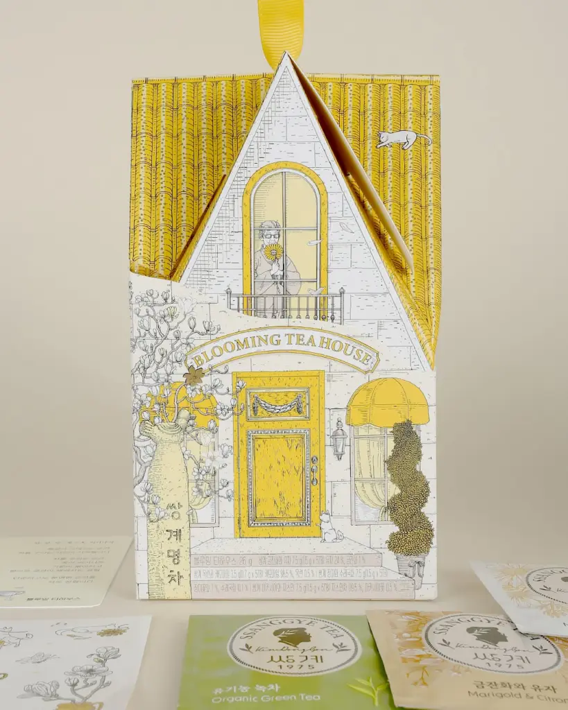 Yellow house-shaped Ssanggye Tea box with sachets arranged in front