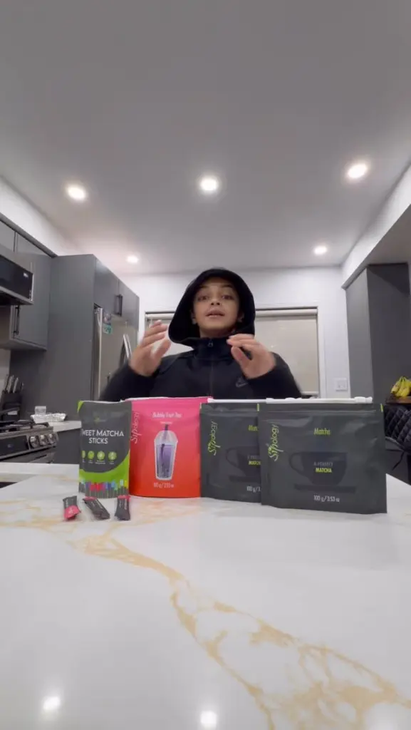 Person standing behind several Sipology tea and matcha packages on a kitchen counter