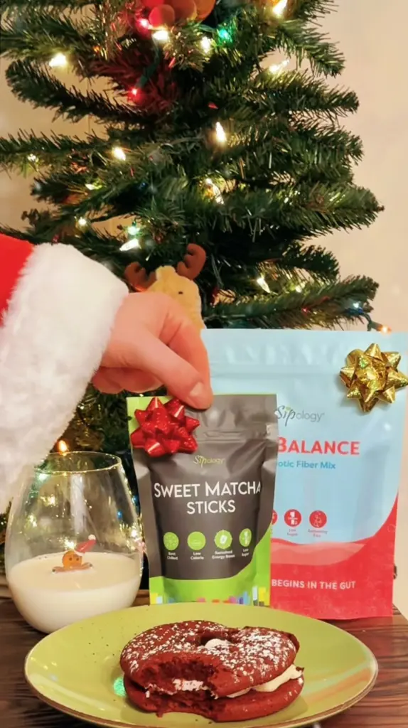 Sweet Matcha Sticks package beside a red sandwich cookie and glass of milk in front of a lit Christmas tree