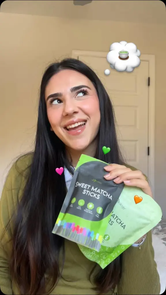 Smiling woman holding two green packages of sweet matcha sticks