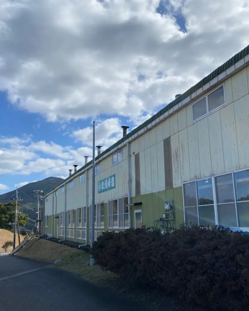 Long pale green industrial building with vents, windows, and a Japanese sign