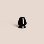 Glossy black ceramic bamboo whisk stand on a pale beige background