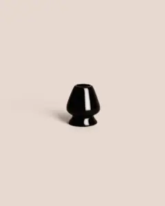 Glossy black ceramic bamboo whisk stand on a pale beige background