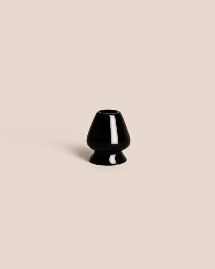 Glossy black ceramic bamboo whisk stand on a pale beige background