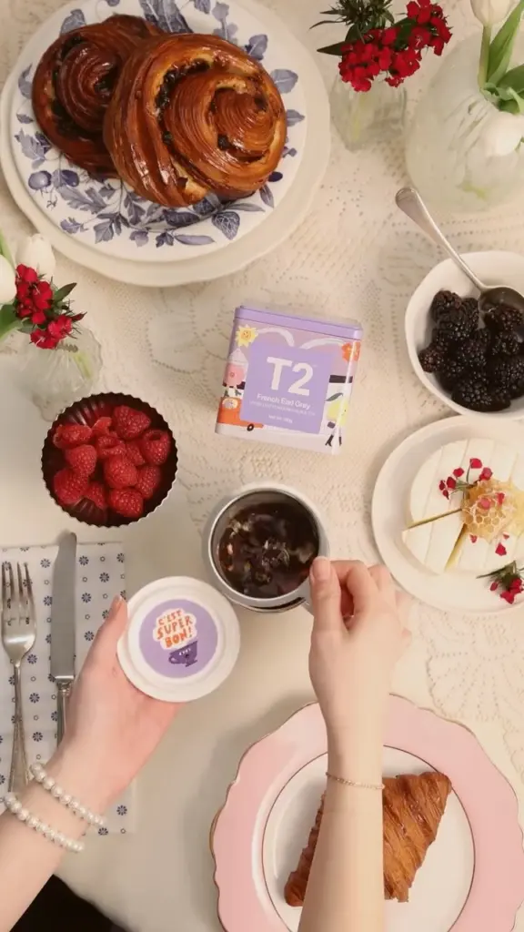 French Earl Grey tin beside tea, pastries, berries, cheese, and flowers
