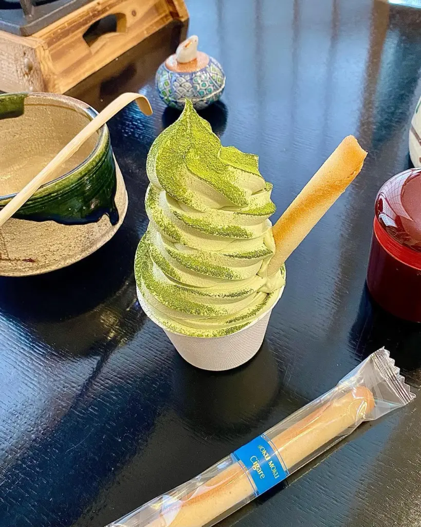 Green matcha soft serve dusted with powder and topped with a wafer stick