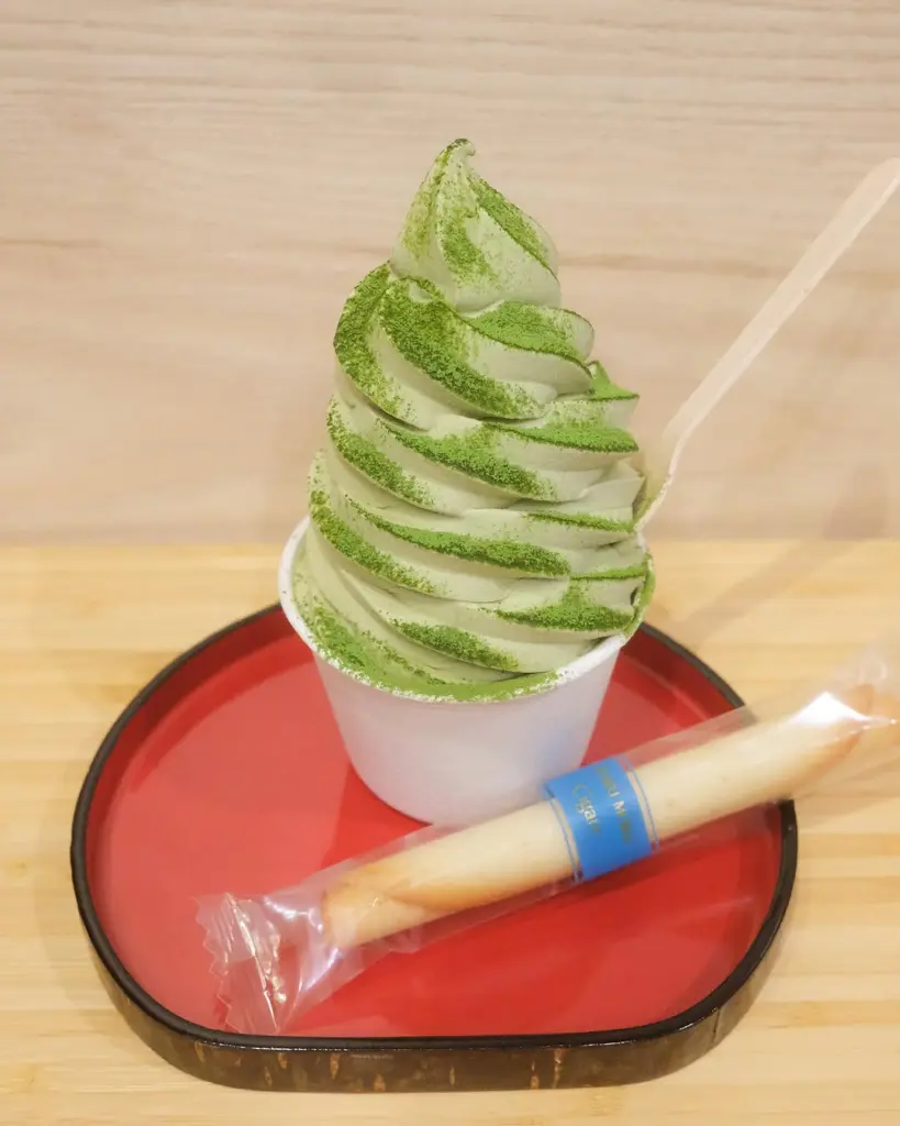 Green soft serve dusted with matcha powder on a red tray