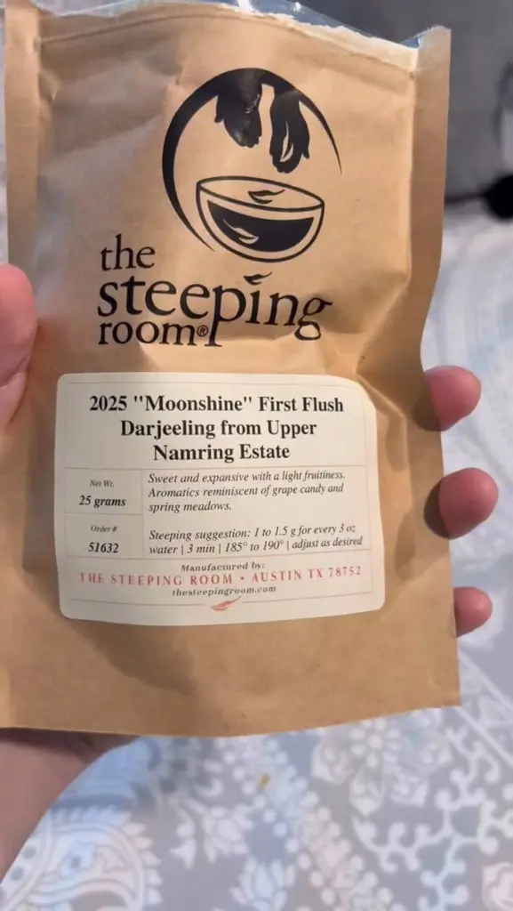 Hand holding a The Steeping Room bag labeled 2025 Moonshine First Flush Darjeeling