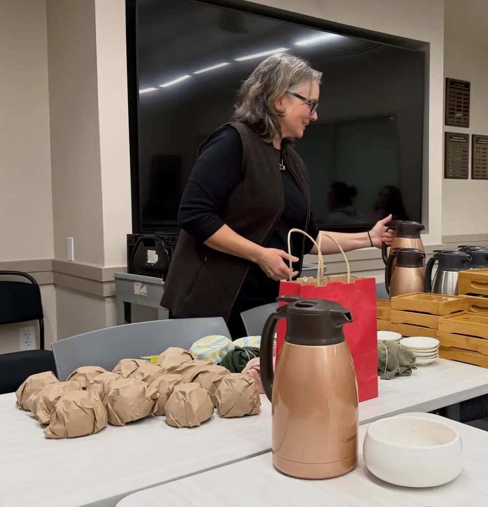 Person arranging insulated carafes beside wrapped parcels, bowls, and wooden trays