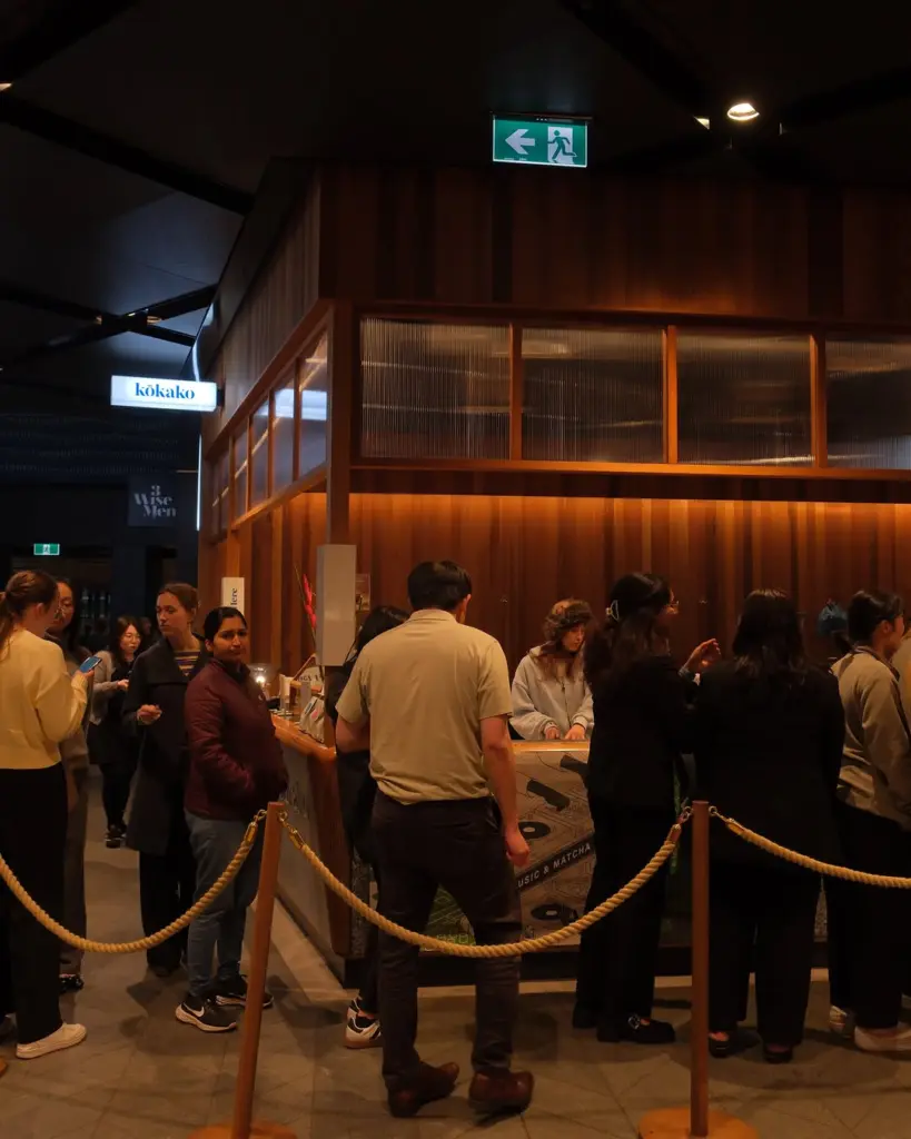 Crowd gathered around a wood-paneled counter behind rope barriers