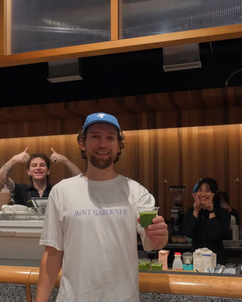 Man presenting a small clear cup filled with bright green matcha