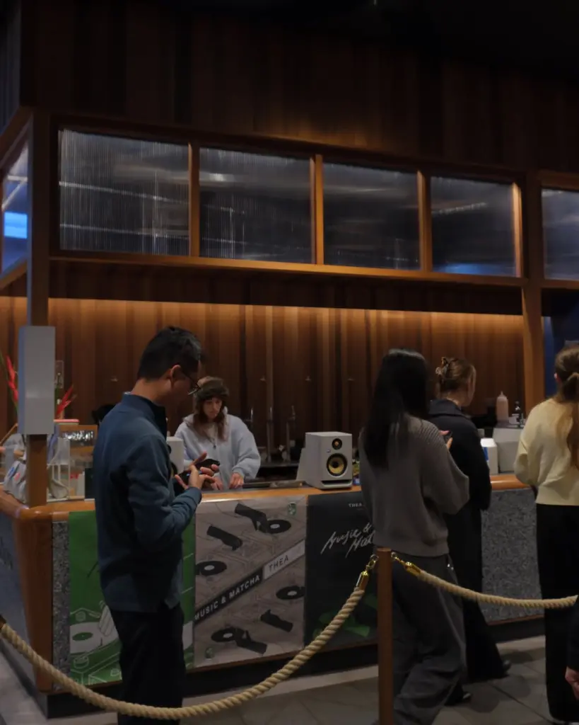 Customers waiting beside a counter decorated with music and matcha graphics