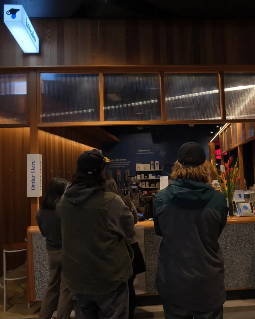 Customers in jackets waiting at a counter beneath an Order Here sign