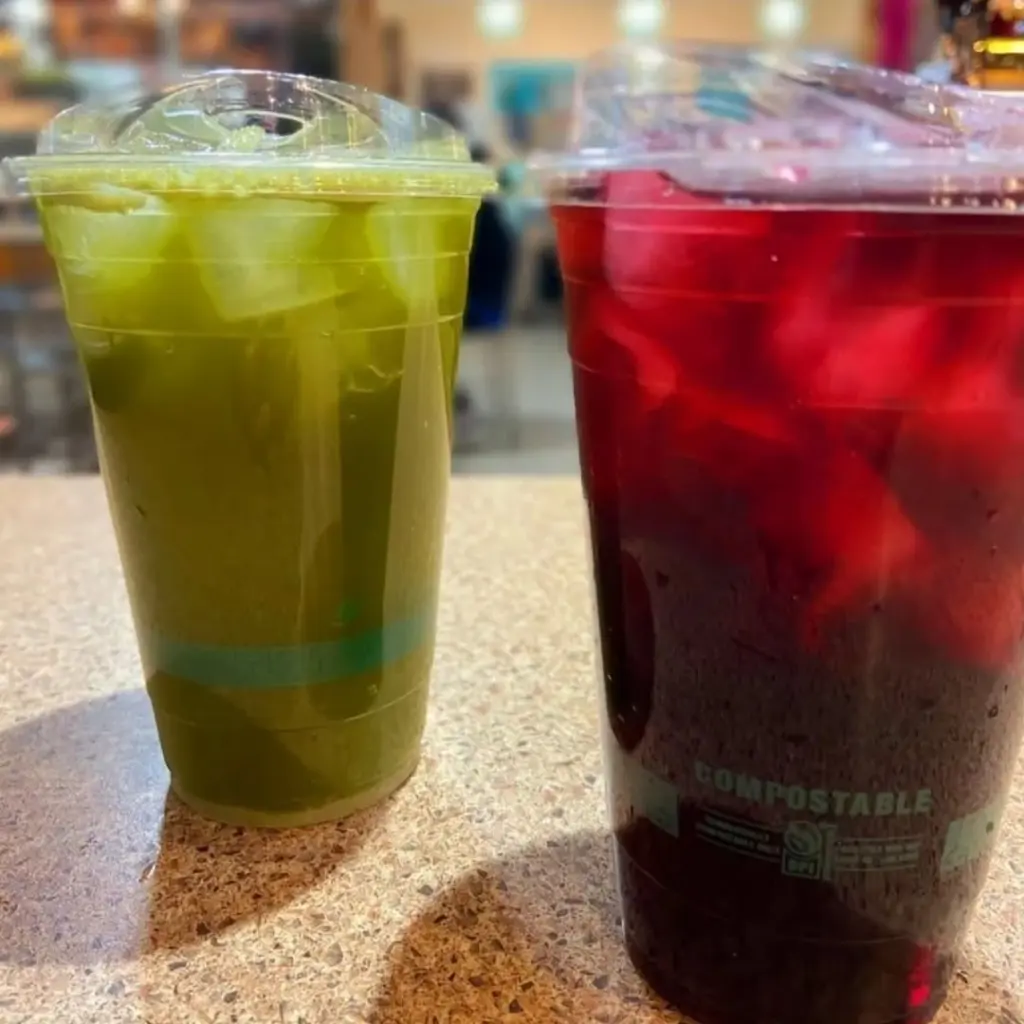 Green and deep red iced drinks in clear lidded cups