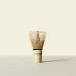 Traditional bamboo chasen standing upright against a pale cream background
