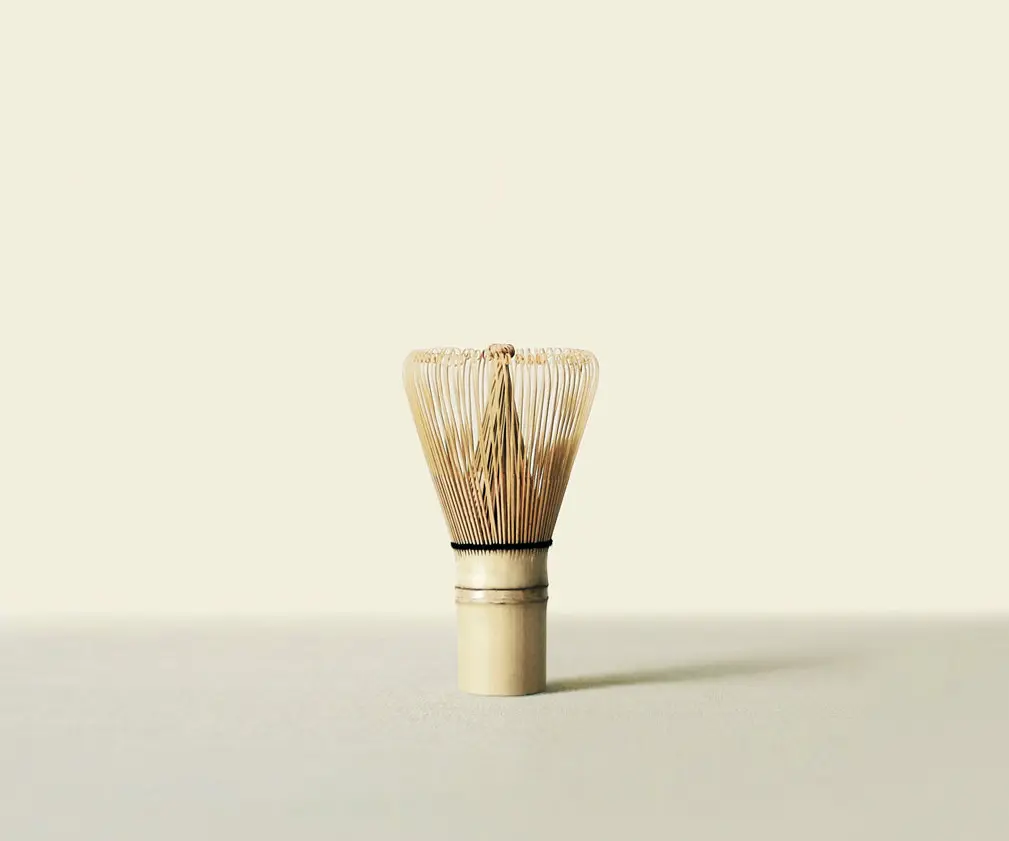 Traditional bamboo chasen standing upright against a pale cream background