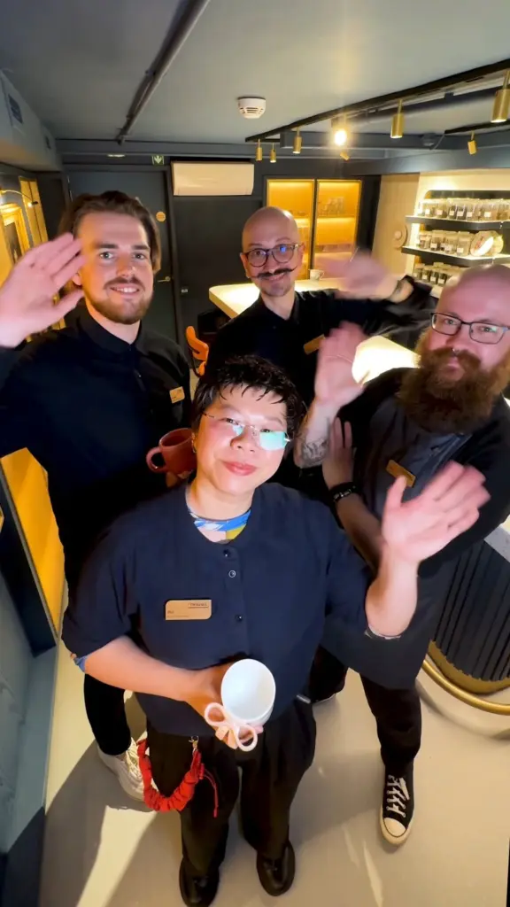 Four team members waving together in a tea shop